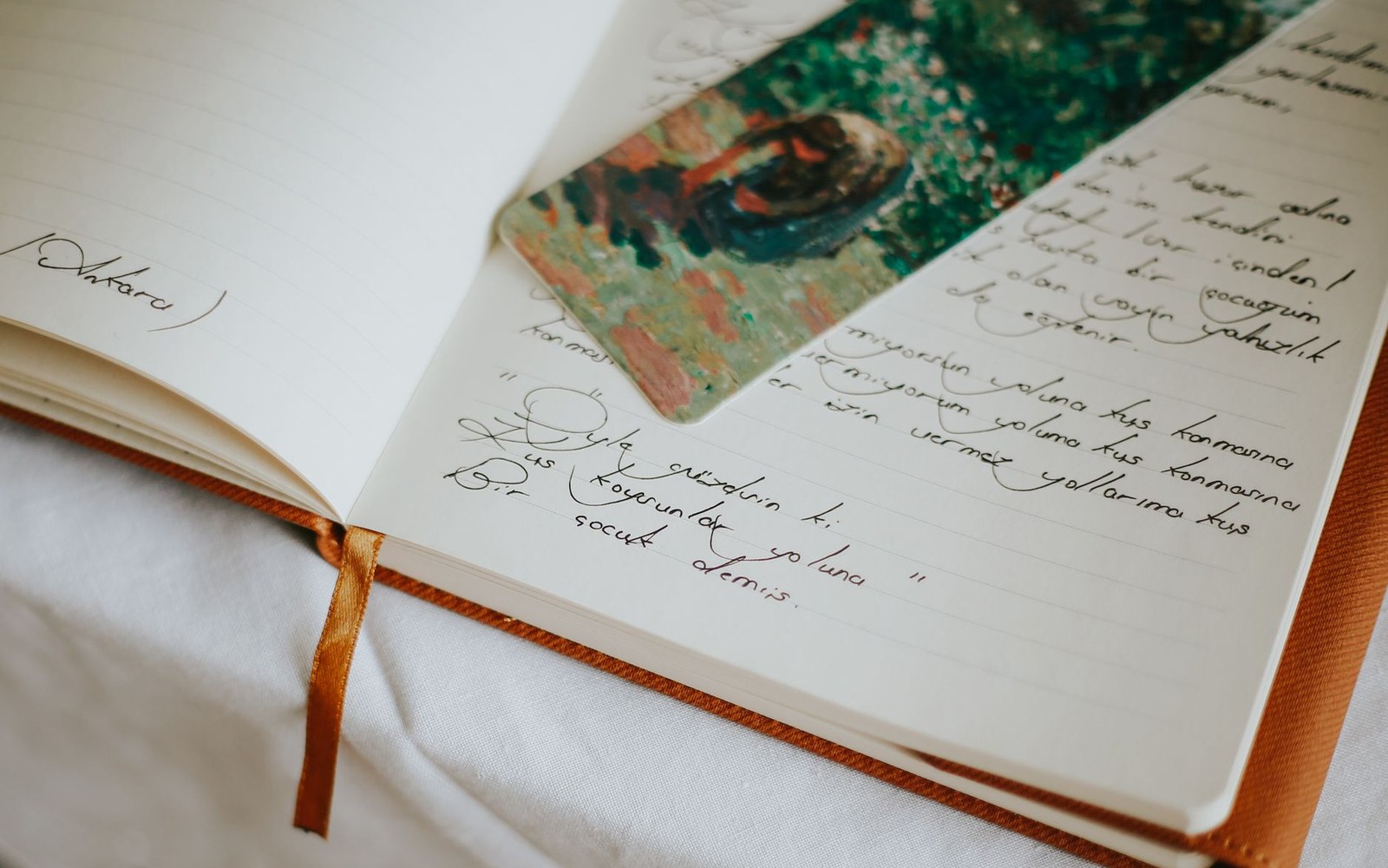 Open journal with handwritten notes and a painted bookmark resting on the pages